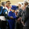 La reine Elizabeth II le 28 mars 2013 à Oxford, accompagnée de son époux le duc d'Edimbourg, distribuant de l'argent comme le veut la tradition lors de la messe de célébration du Jeudi saint.