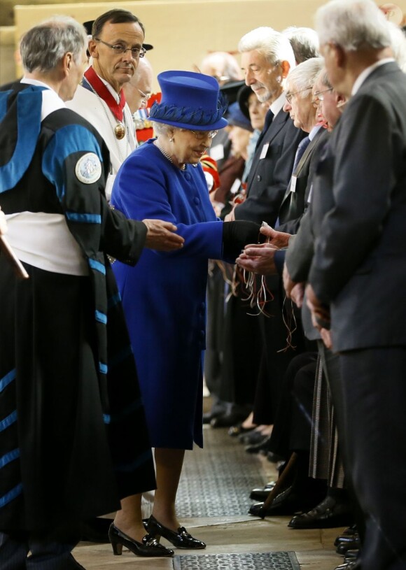 La reine Elizabeth II le 28 mars 2013 à Oxford, accompagnée de son époux le duc d'Edimbourg, distribuant de l'argent comme le veut la tradition lors de la messe de célébration du Jeudi saint.