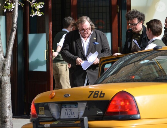 Gérard Depardieu est en train de lire le scenario du film sur DSK d'Abel Ferrara en sortant de son hôtel à New York le 14 avril 2013