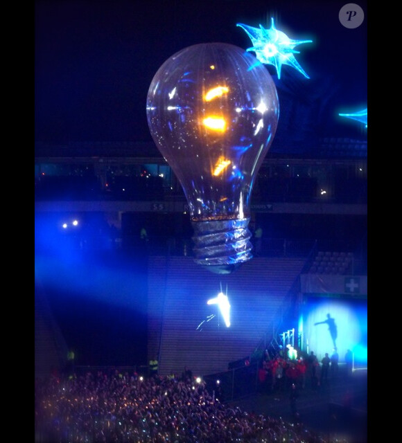 Une acrobate survole le stade perchée sous une ampoule géante pendant le concert de Muse au Stade de France le 21 juin 2013.