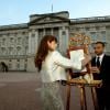 Ailsa Anderson, attachée de presse de la reine Elizabeth II, et Badar Azim, valet du palais royal, mettant en place sur un chevalet dans la cour de Buckingham Palace le bulletin médical annonçant le 22 juillet 2013 la naissance du prince de Cambridge, premier enfant du prince William et de Kate Middleton.