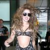 Lady Gaga débarque à l'aéroport d'Heathrow à Londres, habillée d'une combinaison transparente Atelier Versace et de bottines Azzedine Alaïa. Le 27 août 2013.