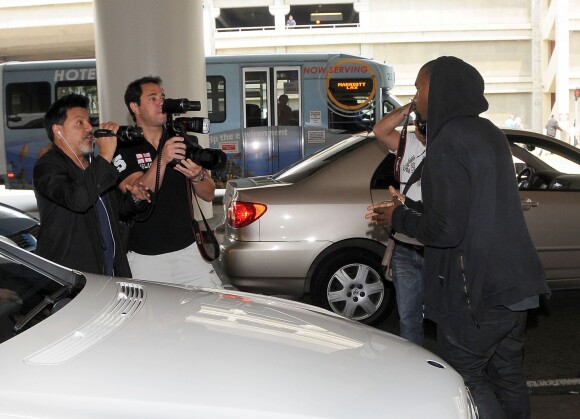 Kanye West tente de déborer la caméra d'un paparazzi à l'aéroport de Los Angeles, le 19 juillet 2013.