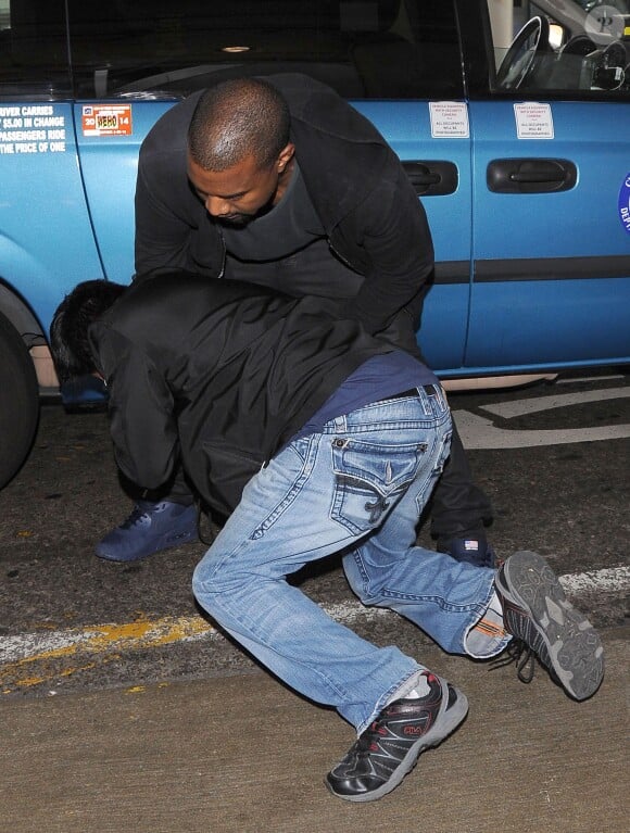Kanye West tente de déborer la caméra d'un paparazzi à l'aéroport de Los Angeles, le 19 juillet 2013.