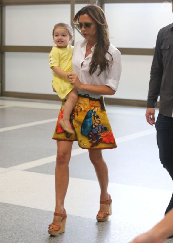 Victoria Beckham et sa fille Harper à l’aéroport de Los Angeles, porte une chemise blanche avec une jupe Carven (collection automne-hiver 2012) et des sandales Chloé. Le 1er juin 2013.