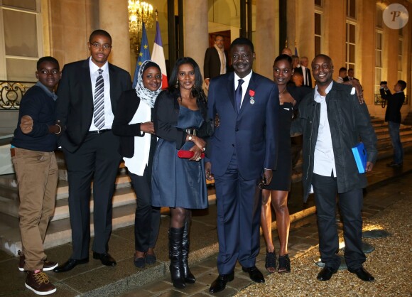 Pape Diouf entouré de sa famille lors de la remise des insignes de la Légion d'honneur et de l'Ordre national du Mérite par François Hollande au Palais de l'Elysée le 9 octobre 2013