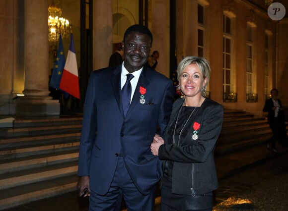 Pape Diouf et Cécile Nowak-Grasso lors de la remise des insignes de la Légion d'honneur et de l'Ordre national du Mérite par François Hollande au Palais de l'Elysée le 9 octobre 2013