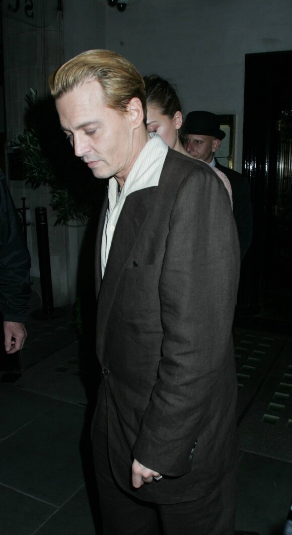 L'acteur américain Johnny Depp, les cheveux blonds, et sa compagne Amber Heard sortant du restaurant Ronnie Scott à Londres, le 25 octobre 2013