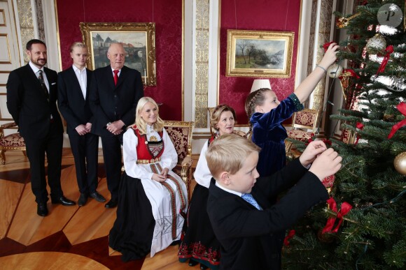 La princesse Mette-Marit de Norvège, la reine Sonja, le prince Haakon, Marius Borg et le roi Harald regardent la princesse Ingrid Isabella et le prince Sverre Magnus décorer le sapin de Noël au palais à Oslo le 19 décembre 2013