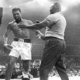 Cassius Clay, aka Mohamed Ali, vient de mettre au tapis Sonny Liston lors de leur combat du 25 mai 1965 à Lewiston. Un combat sur lequel pèse de forts soupçons, comme la première rencontre entre les deux boxeurs du 25 février 1964 pour lequel Sonny Liston aurait touché un million de dollars pour se coucher