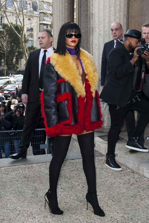 Rihanna arrive au Conseil économique et social pour assister au défilé Miu Miu. Elle porte un manteau, une robe-pull décolletée et un foulard violet Prada, des bas et des sandales noirs. Paris, le 5 mars 2014.