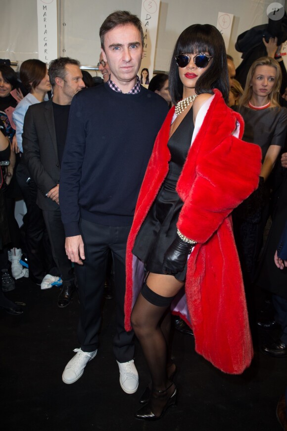 Raf Simons et Rihanna, ultrasexy en manteau rouge en fourrure, petite robe noire en soie (signés Christian Dior) et porte-jarretelles dans les coulisses du défilé Christian Dior prêt-à-porter au Musée Rodin. Paris, le 28 février 2014.