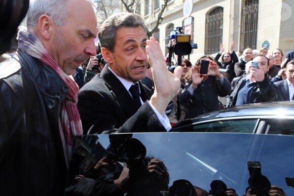 Nicolas Sarkozy regagne sa voiture après être allé voter aux alentours de 13 heures dans le 16e arrondissement de Paris à l'occasion des élections municipales, le 23 mars 2014.