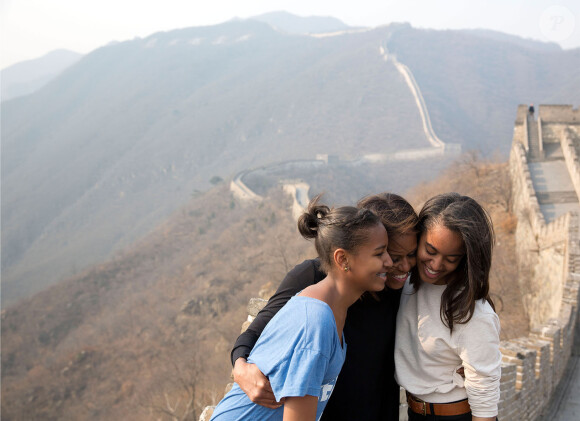 Michelle Obama entourée de ses filles Malia et Sasha lors de son voyage en Chine en mars 2014. Le trio pose fièrement sur la grande muraille de Chine.