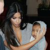 Kim Kardashian et North (protégée par sa maman) arrivent à l'aéroport LAX de Los Angeles le 11 août 2014
