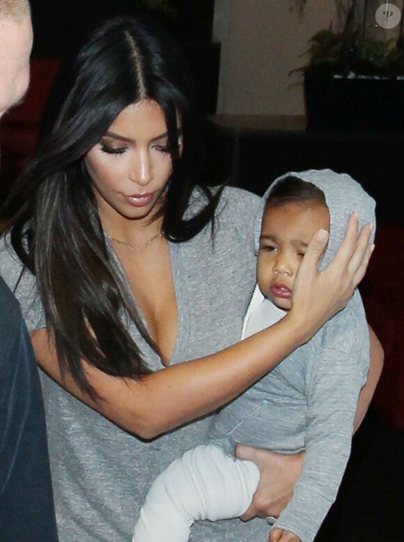 Kim Kardashian et North (protégée par sa maman) arrivent à l'aéroport LAX de Los Angeles le 11 août 2014