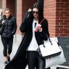 Kendall Jenner à New York, porte avec ses lunettes Ray-Ban vintage et son manteau noir un sac Balmain, un pantalon en cuir et des bottines Alexander Wang (modèle Anouck). Le 22 octobre 2014.