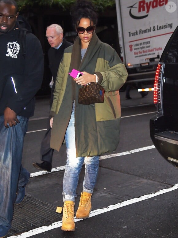 Rihanna arrive à son hôtel à New York, habillée d'un manteau Isabel Marant Etoile, d'un t-shirt gris, d'un jean et de bottines Timberland. Des lunettes de soleil Italia Independent et un sac Louis Vuitton (modèle Twisted Box par Frank Gehry) accessoirisent sa tenue. Le 23 octobre 2014.