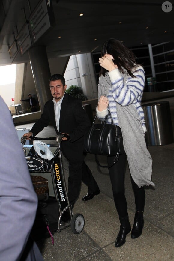 Kendall Jenner arrive à l'aéroport LAX à Los Angeles, habillée d'un sweater rayé H&M, un sac Givenchy (modèle Lucrezia), un pantalon noir et des bottines Alexander Wang. Le 15 novembre 2014.