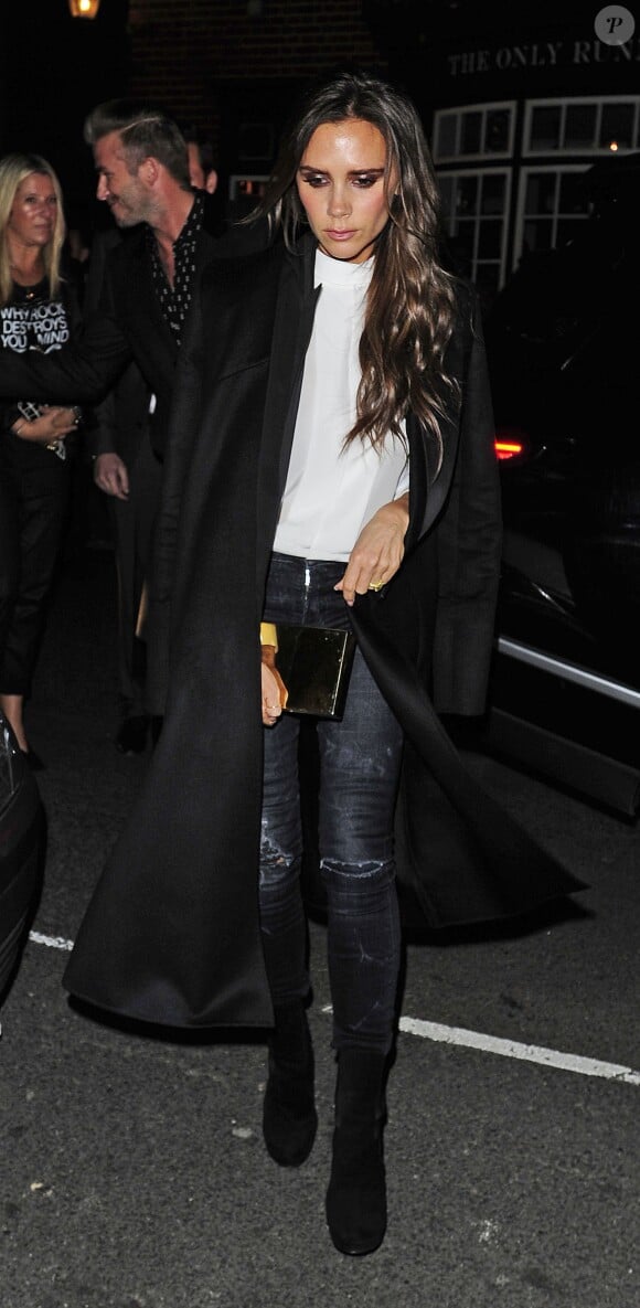 Victoria Beckham arrive au Mark's Club à Londres, habillée d'un manteau et d'une chemise blanche Victoria Beckham, d'un jean R13 et de bottines Alaïa. Le 20 novembre 2014.
