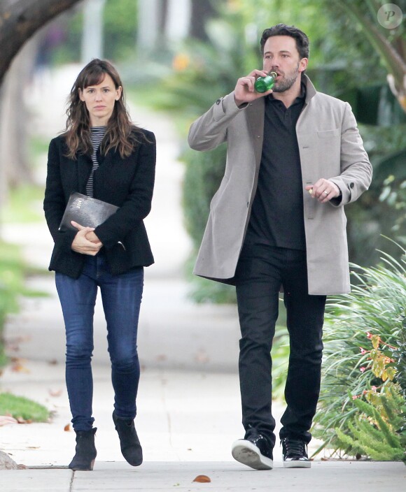 Ben Affleck et sa femme Jennifer Garner, complices dans les rues de Brentwood, le 11 décembre 2014. Ben fume une cigarette et se désaltère ensuite avec un Perrier.