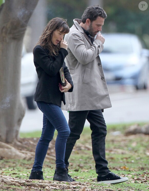 Ben Affleck et sa femme Jennifer Garner, complices dans les rues de Brentwood, le 11 décembre 2014. Ben fume une cigarette et se désaltère ensuite avec un Perrier.