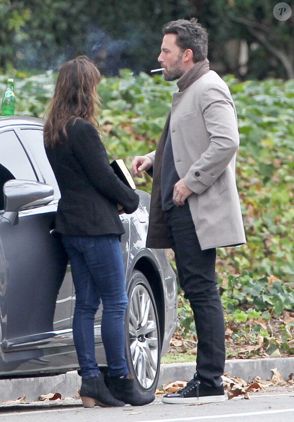 Ben Affleck et sa femme Jennifer Garner, complices dans les rues de Brentwood, le 11 décembre 2014. Ben fume une cigarette et se désaltère ensuite avec un Perrier.