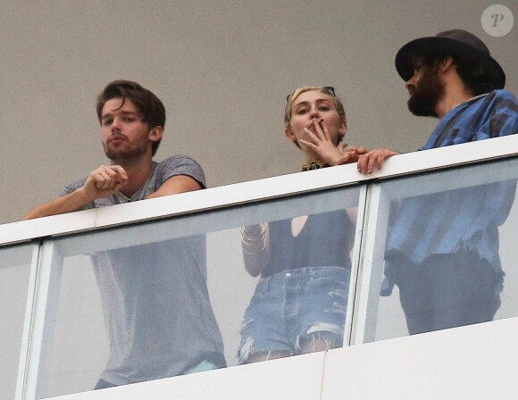 Exclusif - Miley Cyrus et son petit ami Patrick Schwarzenegger fument une drôle de cigarette au balcon de leur chambre d'hôtel à Miami, le 4 décembre 2014