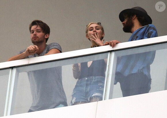 Exclusif - Miley Cyrus et son petit ami Patrick Schwarzenegger fument une drôle de cigarette au balcon de leur chambre d'hôtel à Miami, le 4 décembre 2014