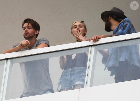 Exclusif - Miley Cyrus et son petit ami Patrick Schwarzenegger fument une drôle de cigarette au balcon de leur chambre d'hôtel à Miami, le 4 décembre 2014