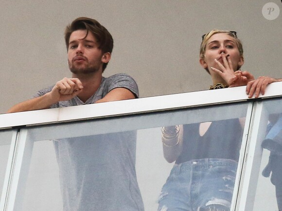 Exclusif - Miley Cyrus et son petit ami Patrick Schwarzenegger fument une drôle de cigarette au balcon de leur chambre d'hôtel à Miami, le 4 décembre 2014