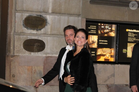 La princesse Madeleine de Suède, enceinte et souriante, quitte la Bourse de Stockholm à l'issue de la soirée de l'Académie de Suède avec son mari Chris O'Neill. Le 20 décembre 2014.
