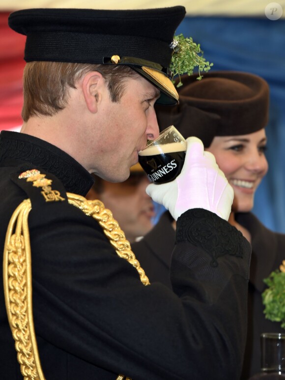 Le prince William boit une Guinness devant son épouse Kate Middleton le 17 mars 2015 à la base des Irish Guards lors de la Saint Patrick.