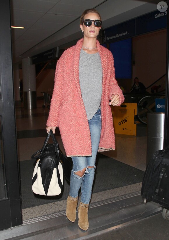 Rosie Huntington-Whiteley arrive à l'aéroport LAX de Los Angeles, habillée d'un manteau à chevrons Isabel Marant (modèle Gabriel), d'un t-shirt gris, d'un jean Paige et de bottines Saint Laurent. Des lunettes Karen Walker et un sac Chloé (modèle Alice) accessoirisent sa tenue. Le 5 mai 2015.
