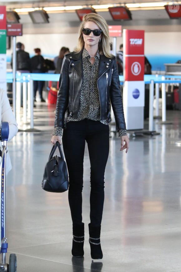 Rosie Huntington-Whiteley à l'aéroport JFK à New York, porte un perfecto, une chemise et des bottines Saint Laurent, un jean noir Paige et un sac Givenchy (modèle Lucrezia). Le 3 mai 2015.