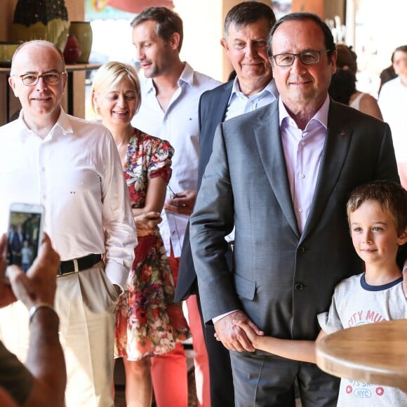 Exclusif - François Hollande et Bernard Cazeneuve se promènent dans le village de Aiguines (dans le Var) où le premier a fêté ses 61 ans et assisté au mariage de son ministre de l'intérieur, le 12 août 2015. Un remariage, avec Véronique que l'on peut voir en arrière-plan en robe fleurie, dans le plus grand secret dont on apprend à peine l'existence.