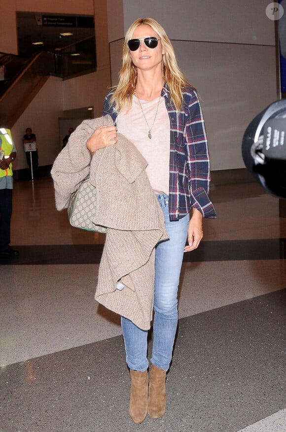 Heidi Klum arrive à l'aéroport de LAX à Los Angeles chaussée de bottines Saint Laurent et tenant à la main son cardigan Chloé et son sac Gucci. Le 22 octobre 2015.