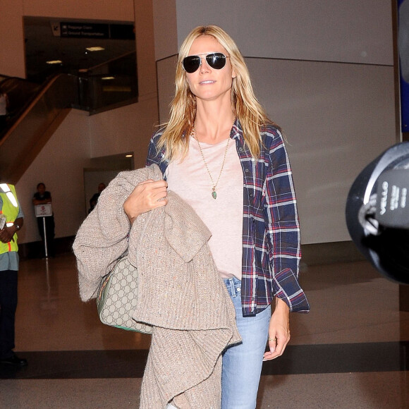 Heidi Klum arrive à l'aéroport de LAX à Los Angeles chaussée de bottines Saint Laurent et tenant à la main son cardigan Chloé et son sac Gucci. Le 22 octobre 2015.