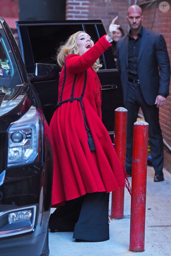 La chanteuse Adele salue ses fans habillée d'un manteau rouge au Joe's pub de New York le 20 novembre 2015.