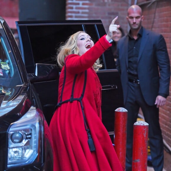 La chanteuse Adele salue ses fans habillée d'un manteau rouge au Joe's pub de New York le 20 novembre 2015.