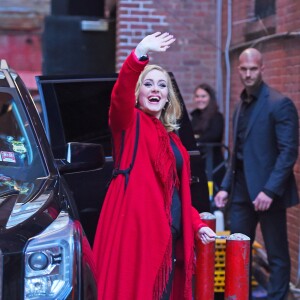 La chanteuse Adele salue ses fans habillée d'un manteau rouge au Joe's pub de New York le 20 novembre 2015.