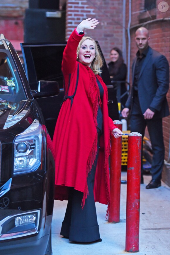 La chanteuse Adele salue ses fans habillée d'un manteau rouge au Joe's pub de New York le 20 novembre 2015.