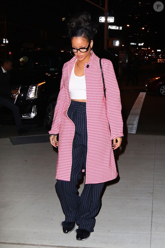 Rihanna arrive au restaurant Nobu à New York, habillée d'un manteau et d'un pantalon Céline (collection croisière 2016), d'un crop-top blanc et de baskets Pierre Hardy. La chanteuse de 27 ans porte également un sac Mark Cross (modèle Benchley). Le 2 janvier 2016.