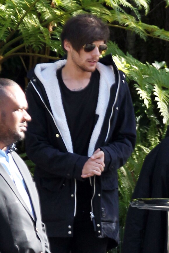 Louis Tomlinson du groupe One Direction quitte son hôtel, son assistant charge une guitare et une XBOX dans la voiture à Beverly Hills le 28 janvier 2016