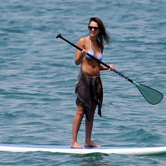 Jessica Alba profite d'une belle journée ensoleillée pour bronzer et faire du paddle sur une plage à Maui à Hawaii. Son mari Cash Warren se baigne seul en attendant. Le  22 mars 2016.