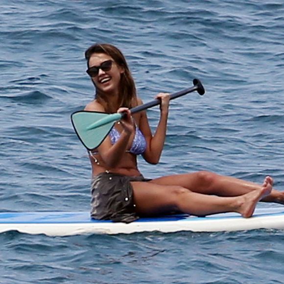 Jessica Alba profite d'une belle journée ensoleillée pour bronzer et faire du paddle sur une plage à Maui à Hawaii. Son mari Cash Warren se baigne seul en attendant. Le  22 mars 2016.