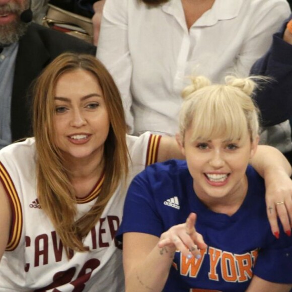 Miley Cyrus, sa grande soeur Brandi et Victor Cruz (New York Giants, NFL) assistent au match de NBA New York Knicks vs. Cleveland Cavaliers au Madison Square Garden. New York, le 26 mars 2016.