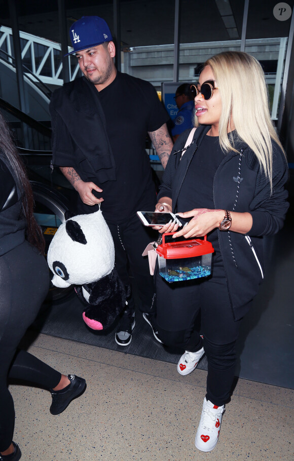 Rob Kardashian et sa compagne Blac Chyna arrivent à l'aéroport LAX de Los Angeles, Rob a ramené une énorme peluche, Los Angeles le 27 Mars 2016. Rob Kardashian and Blac Chyna arrive at LAX airport, Rob was carrying a large stuffed animal and smiling as they made their way to their car in Los Angeles on March 27, 2016.27/03/2016 - Los Angeles
