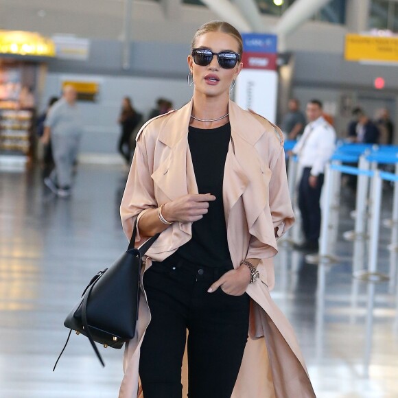 Rosie Huntington-Whiteley arrive à l'aéroport de JFK à New York, habillée d'un trench-coat en soie Stella McCartney, d'un t-shirt noir James Perse, d'un jean noir PAIGE® et de sandales Gianvito Rossi. Des lunettes de soleil Saint Laurent et un sac CÉLINE (modèle Mini Belt) accessoirisent sa tenue. Le 27 avril 2016.