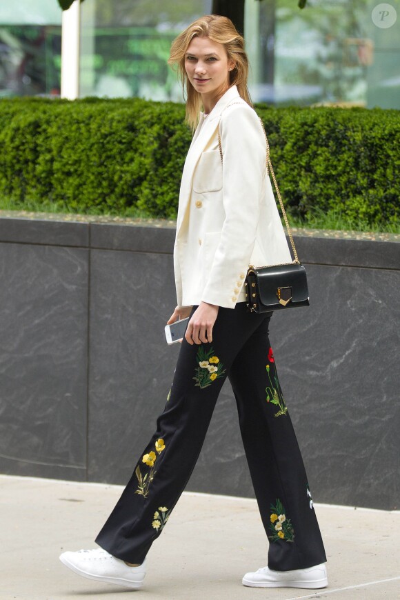 Karlie Kloss à New York, porte un blazer et un t-shirt blancs, un pantalon à broderies florales Stella McCartney (modèle Kassidy), un sac Jimmy Choo (modèle Lockett) et des baskets adidas x Raf Simons (modèle Stan Smith). Le 26 avril 2016.